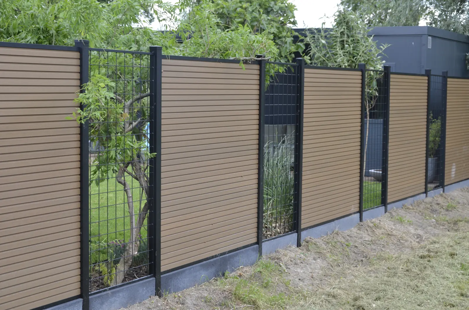 Schutting achter de beplanting, half aan het oog onttrokken