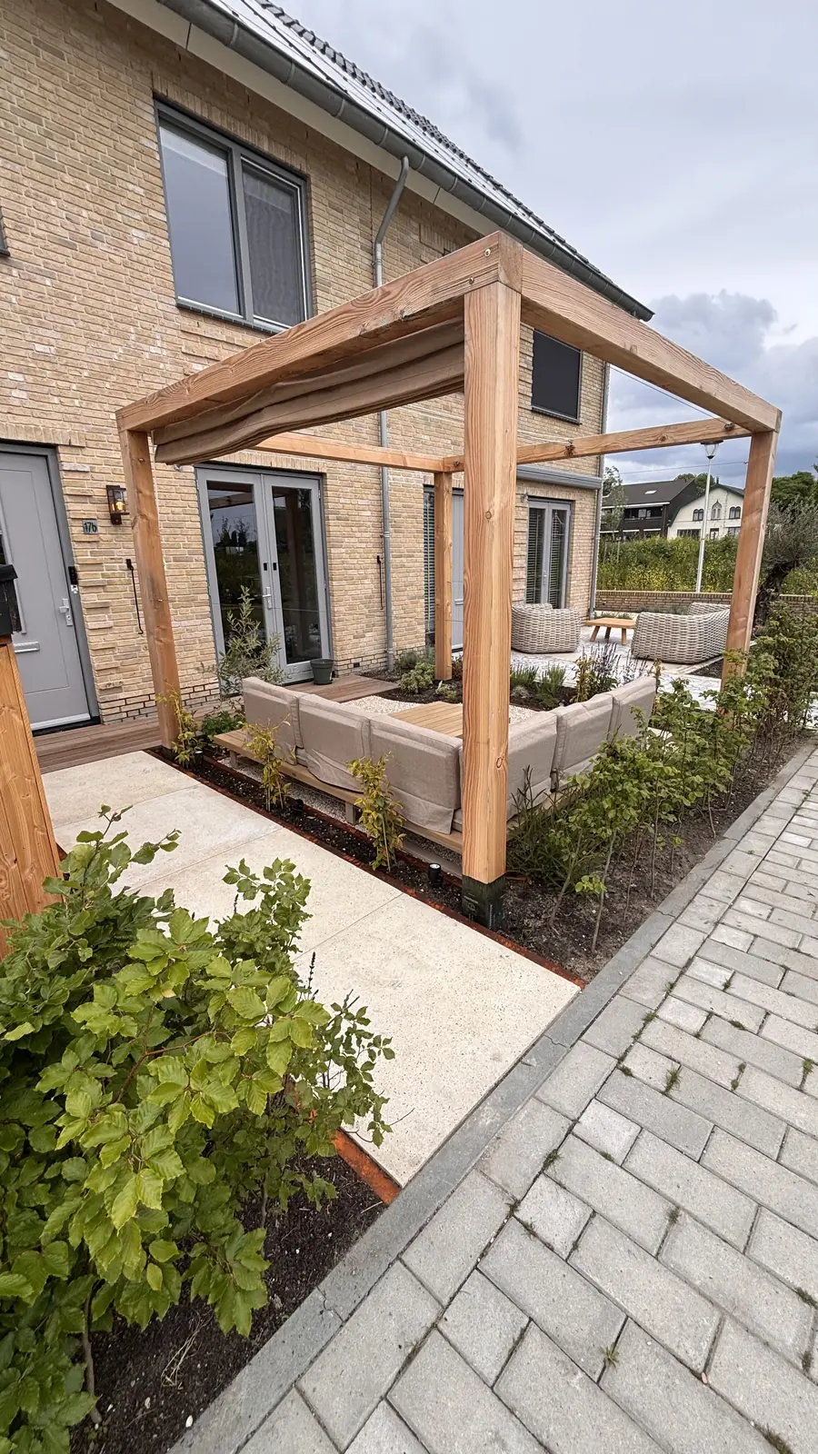 De voorzijde van de woning met pergola en nieuwe beplanting