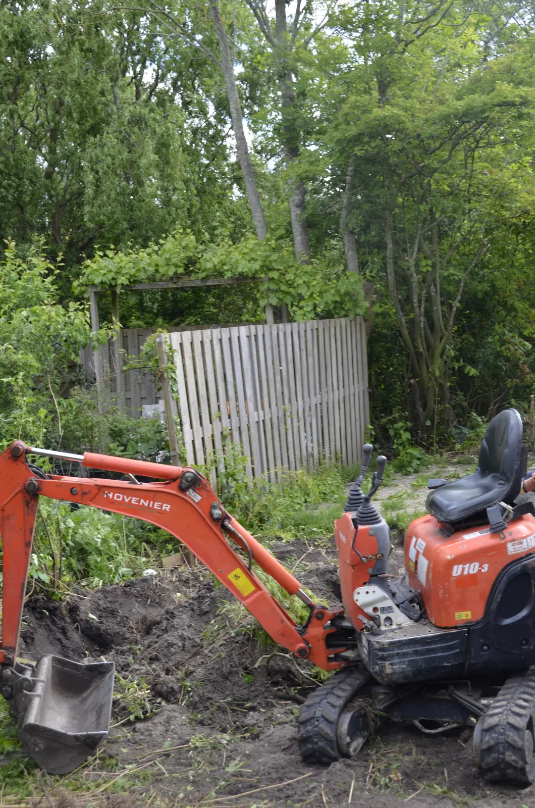 Onze minigraafmachine in de tuin, met de uitgegraven grond ernaast