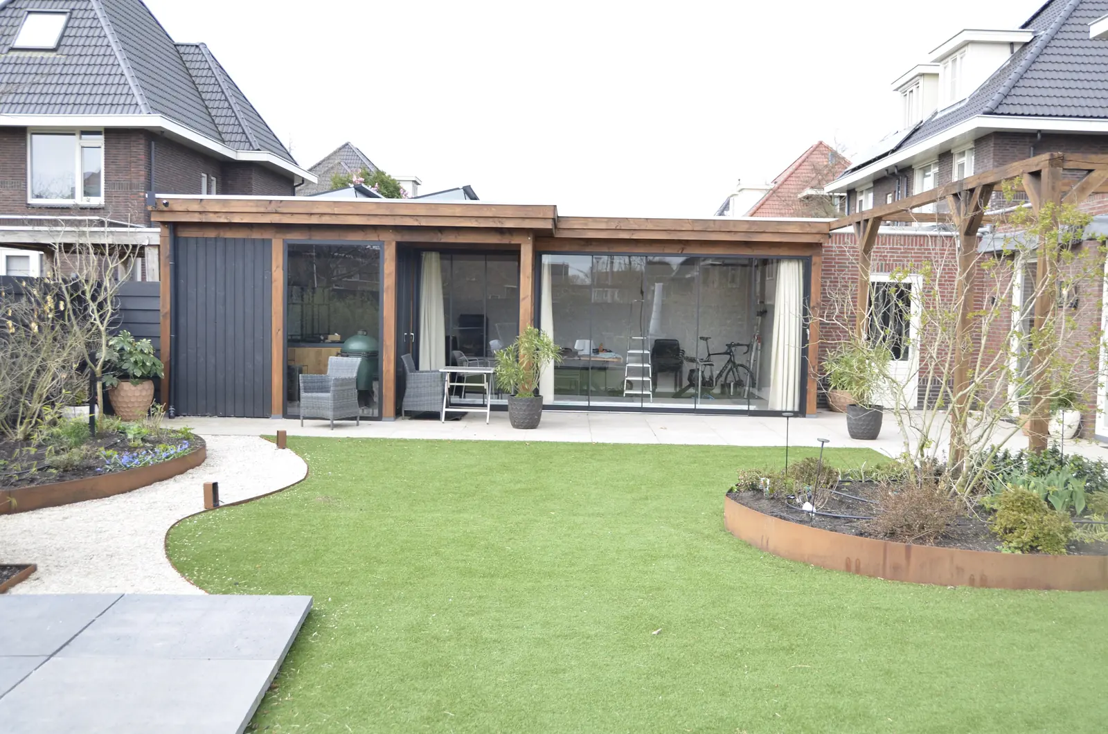 Douglas overkapping naast een ronde border met cortenstalen rand en jonge heesters