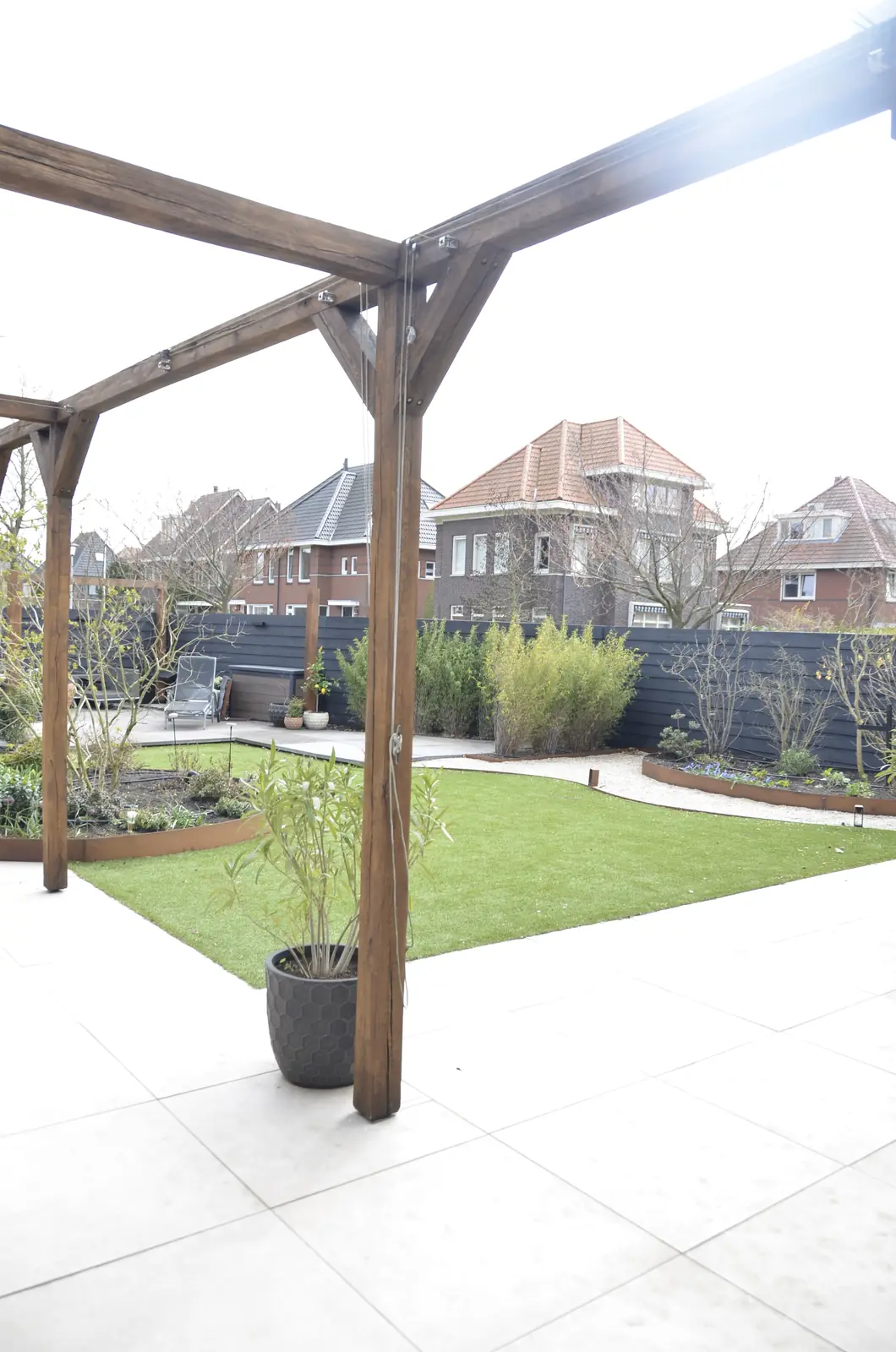 De overkapping staat er, de tuin eromheen is nog zand met gereedschap en een kruiwagen