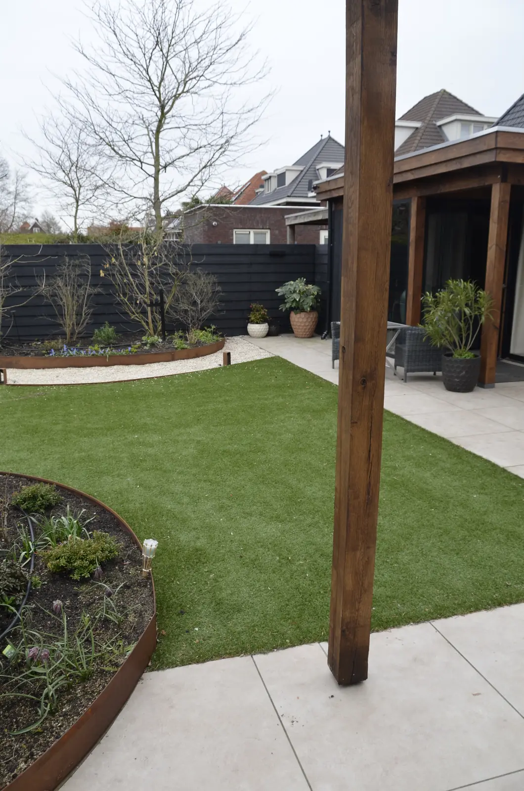 Gazon met cortenstalen rand, het terraspad en een staander van de overkapping