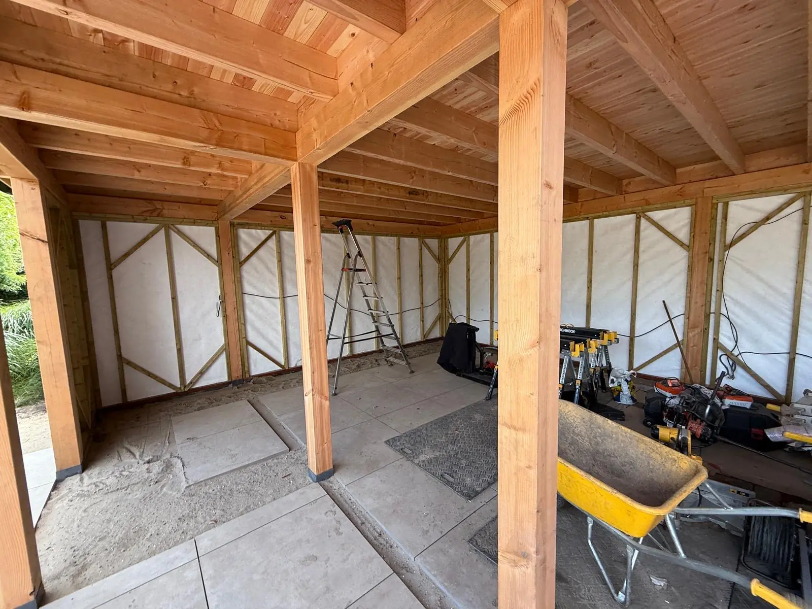 Binnen in de overkapping tijdens de bouw, met kruiwagen en materiaal