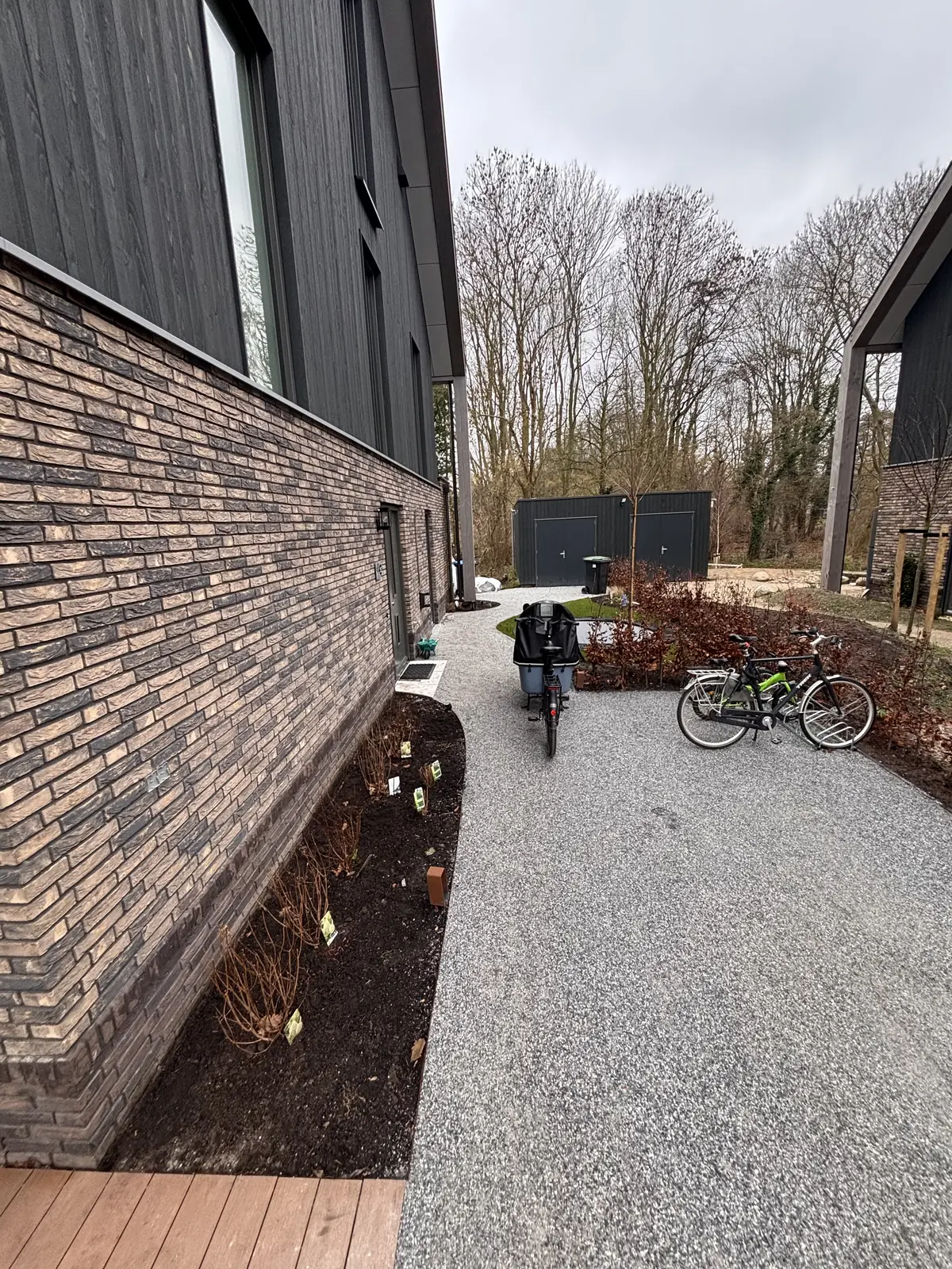 Grindpad langs de gevel met een border van jonge heesters