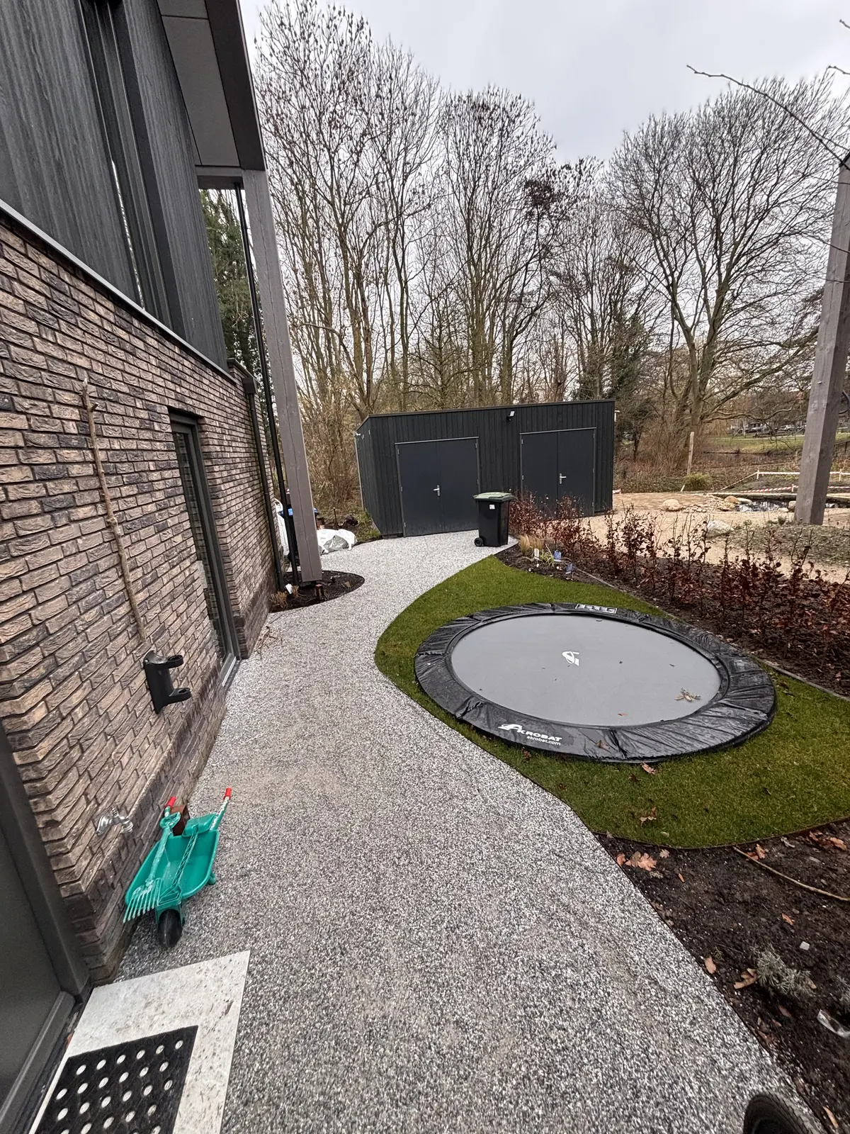 Ingegraven trampoline in het gazon, omzoomd door grind