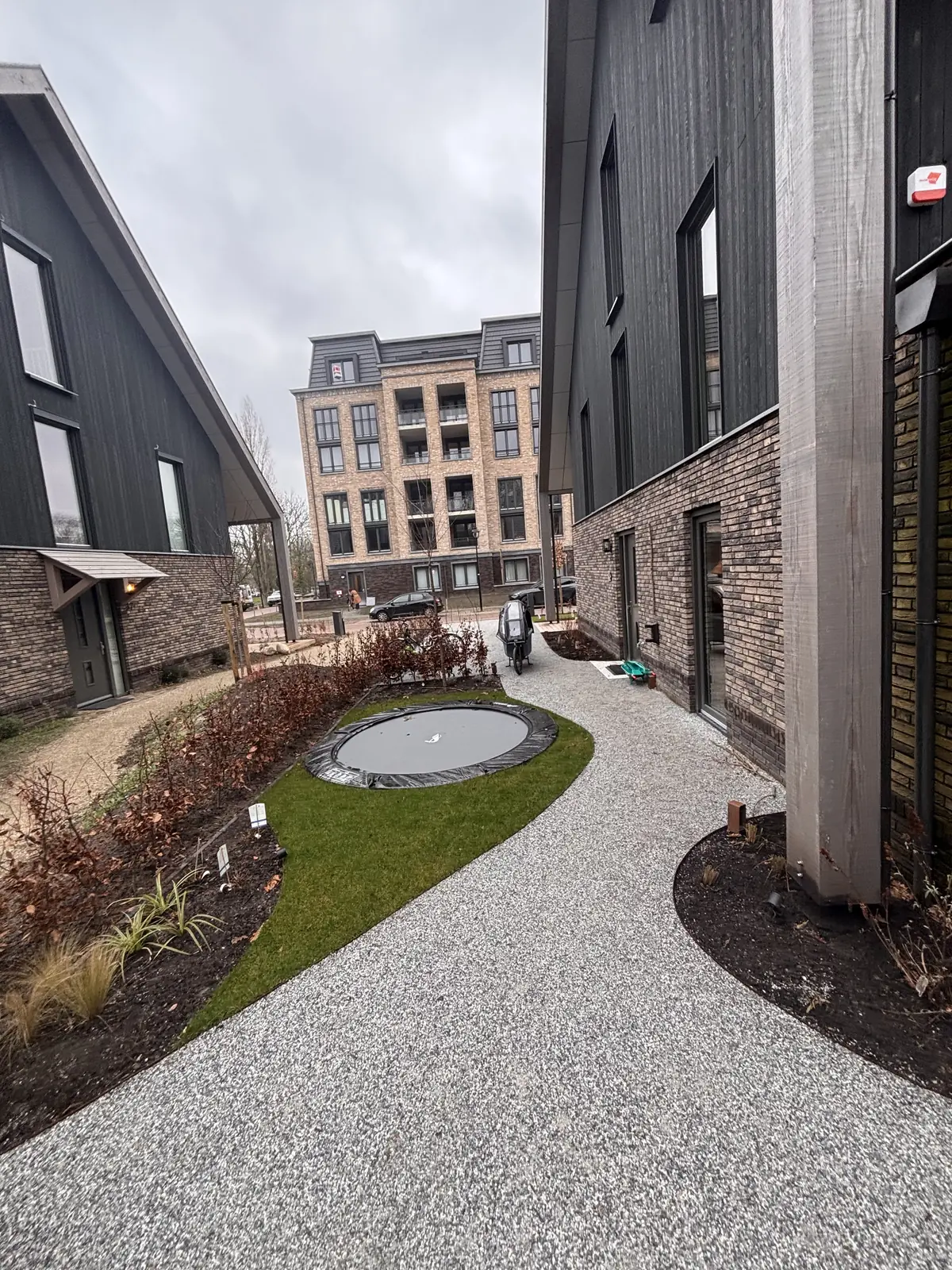Doorkijk tussen de woningen over het grindpad