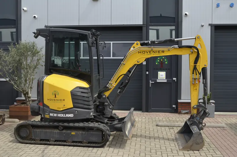 Onze New Holland graafmachine van opzij, met de dieplepelbak ernaast