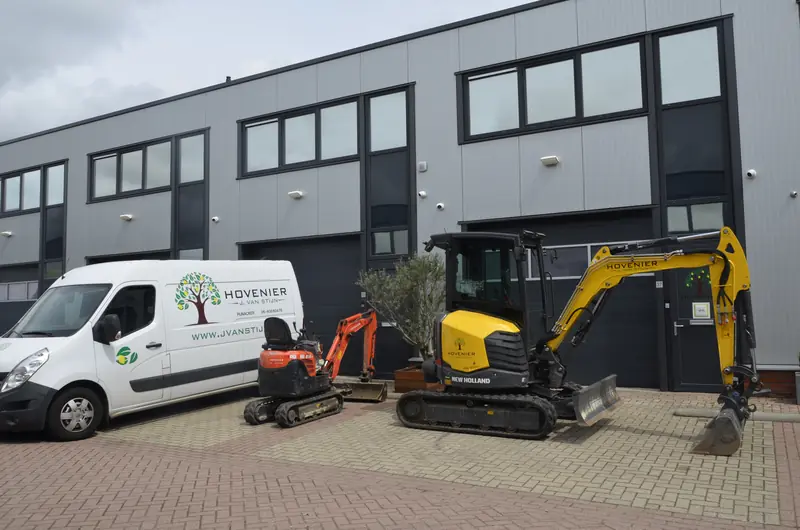 Bedrijfsbus, minigraver en de New Holland naast elkaar voor het pand
