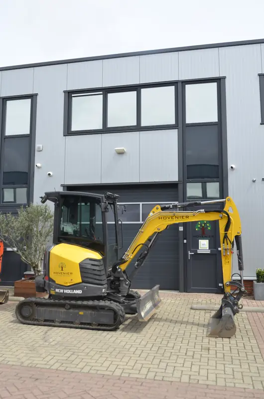 De New Holland graafmachine met sloophamerbak, klaar om geladen te worden