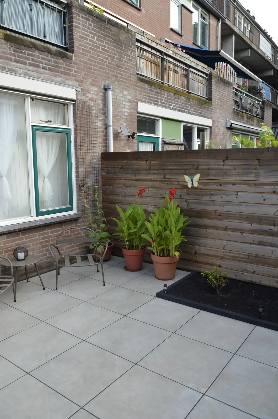 Het terras met de border en de balkons van de buren erboven