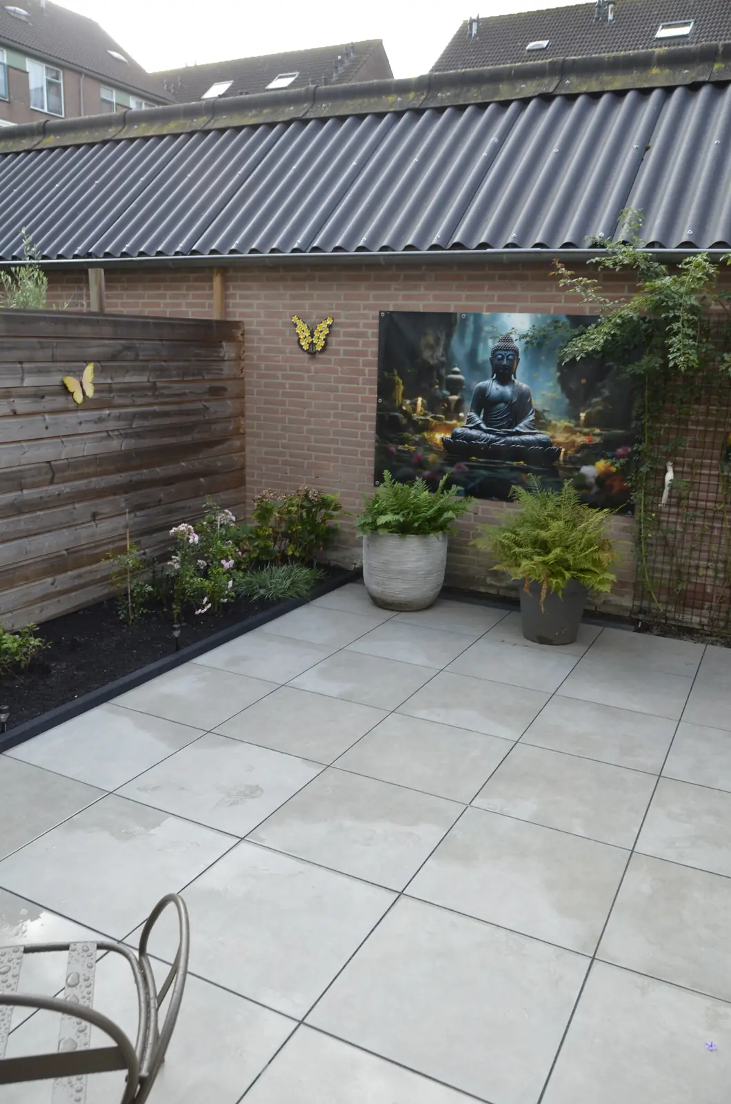 Overzicht van de binnentuin met schutting, poster en beplanting