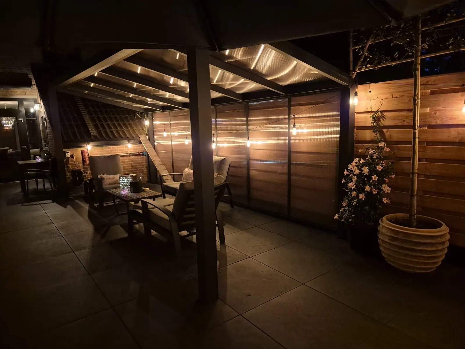 De veranda in de avond, met lichtsnoer en loungebank onder het dak