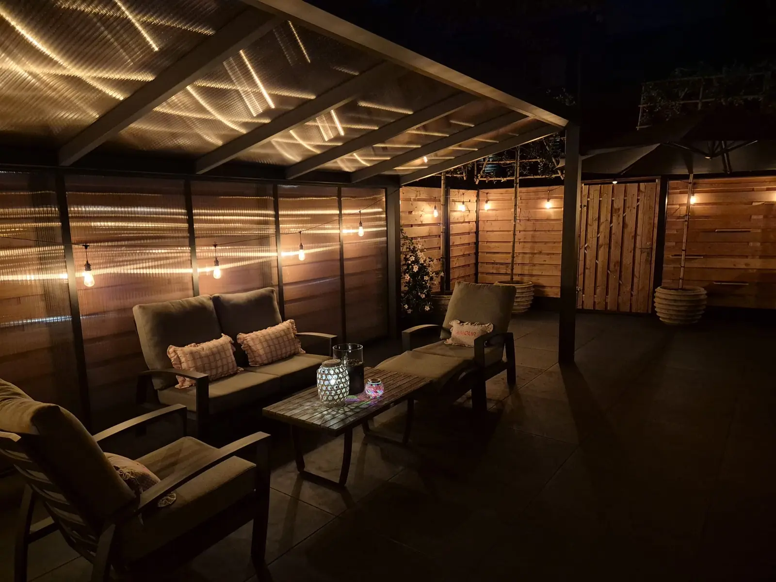 Loungeset onder de aluminium veranda met doorzichtig dak