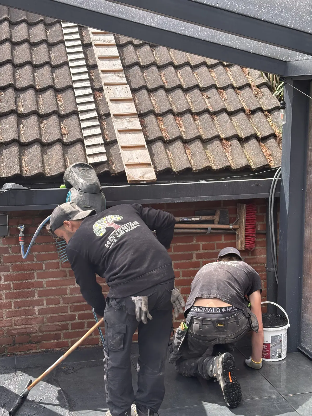 Twee hoveniers werken aan de aansluiting op het dak