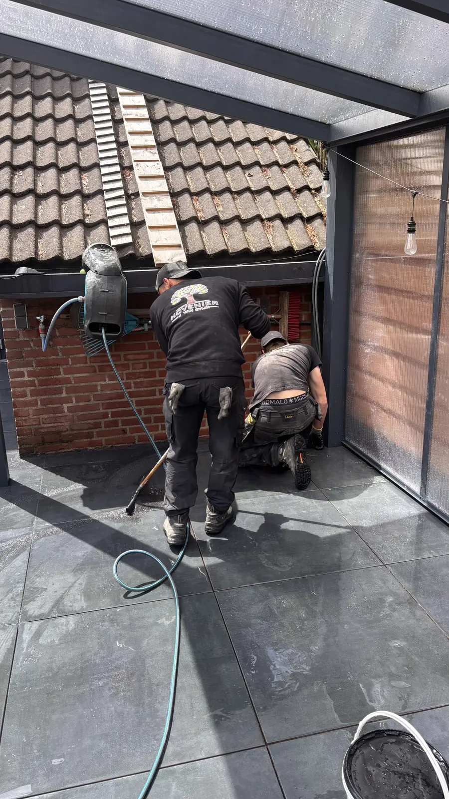 Hovenier aan het werk in de hoek bij de schutting