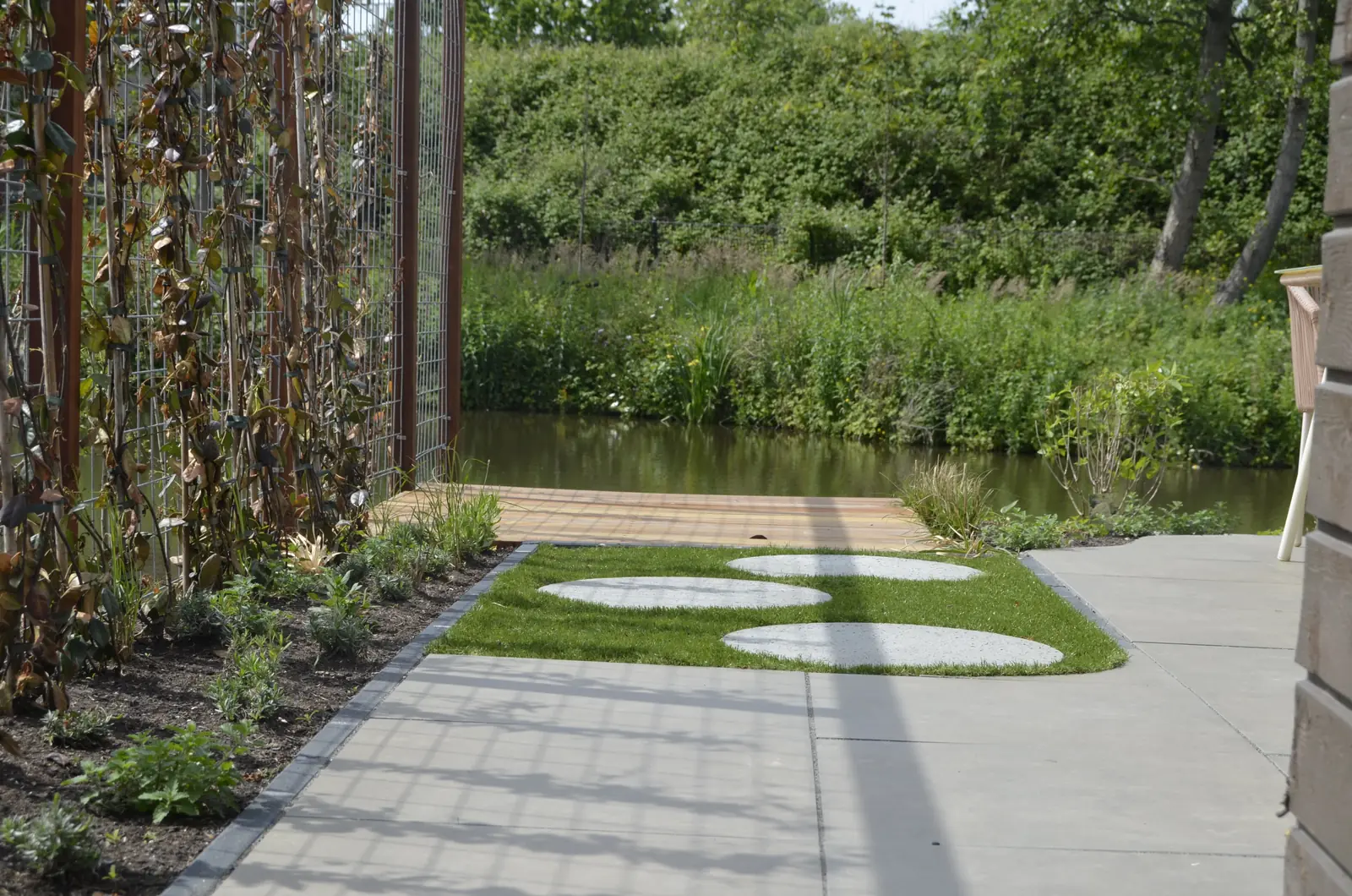 De woning aan het water voor de aanleg: kale grond tot aan de oever