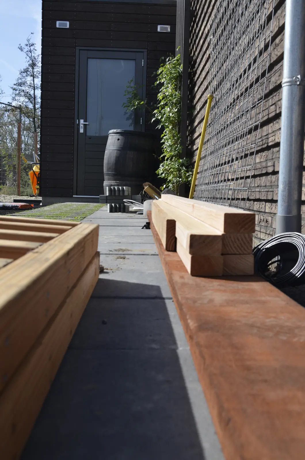 De zijtuin tijdens de aanleg, met hout klaar voor de vlonder